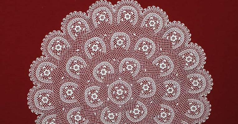 Close-up detail of a finely crafted embroidery, featuring a delicate semicircular structure.