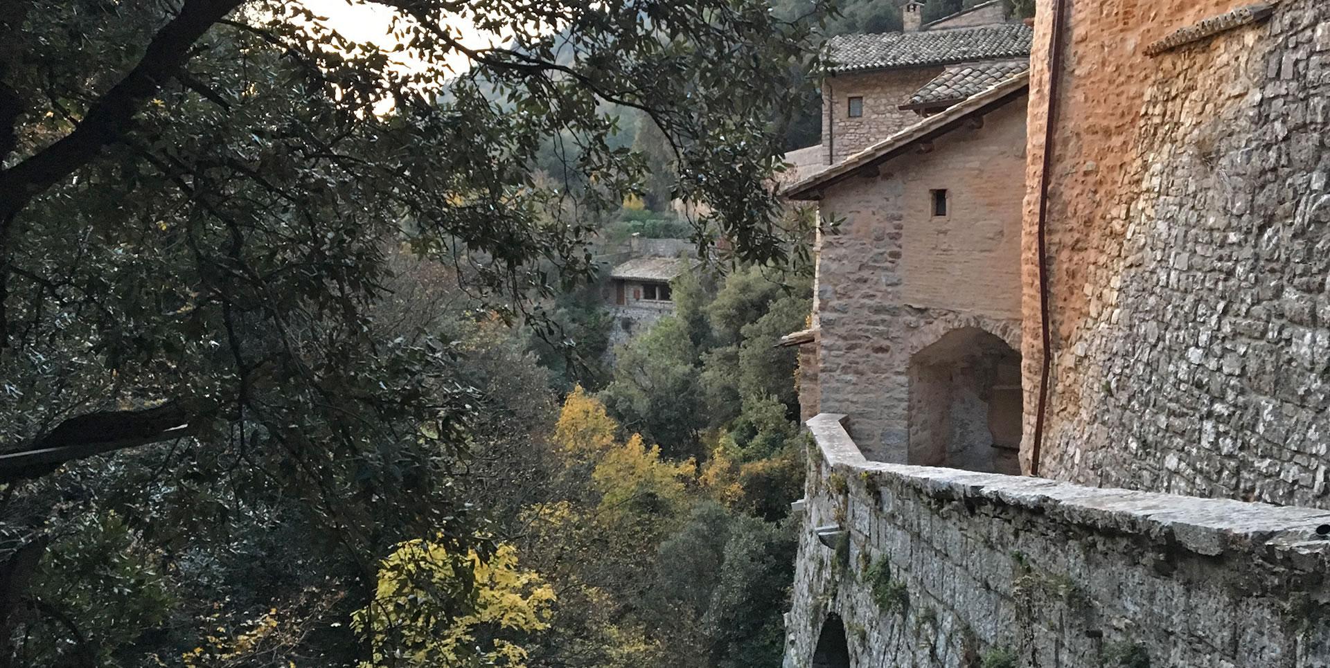 Ancient stone walls of the Eremo delle Carceri overlooking the wooded valley of Mount Subasio.