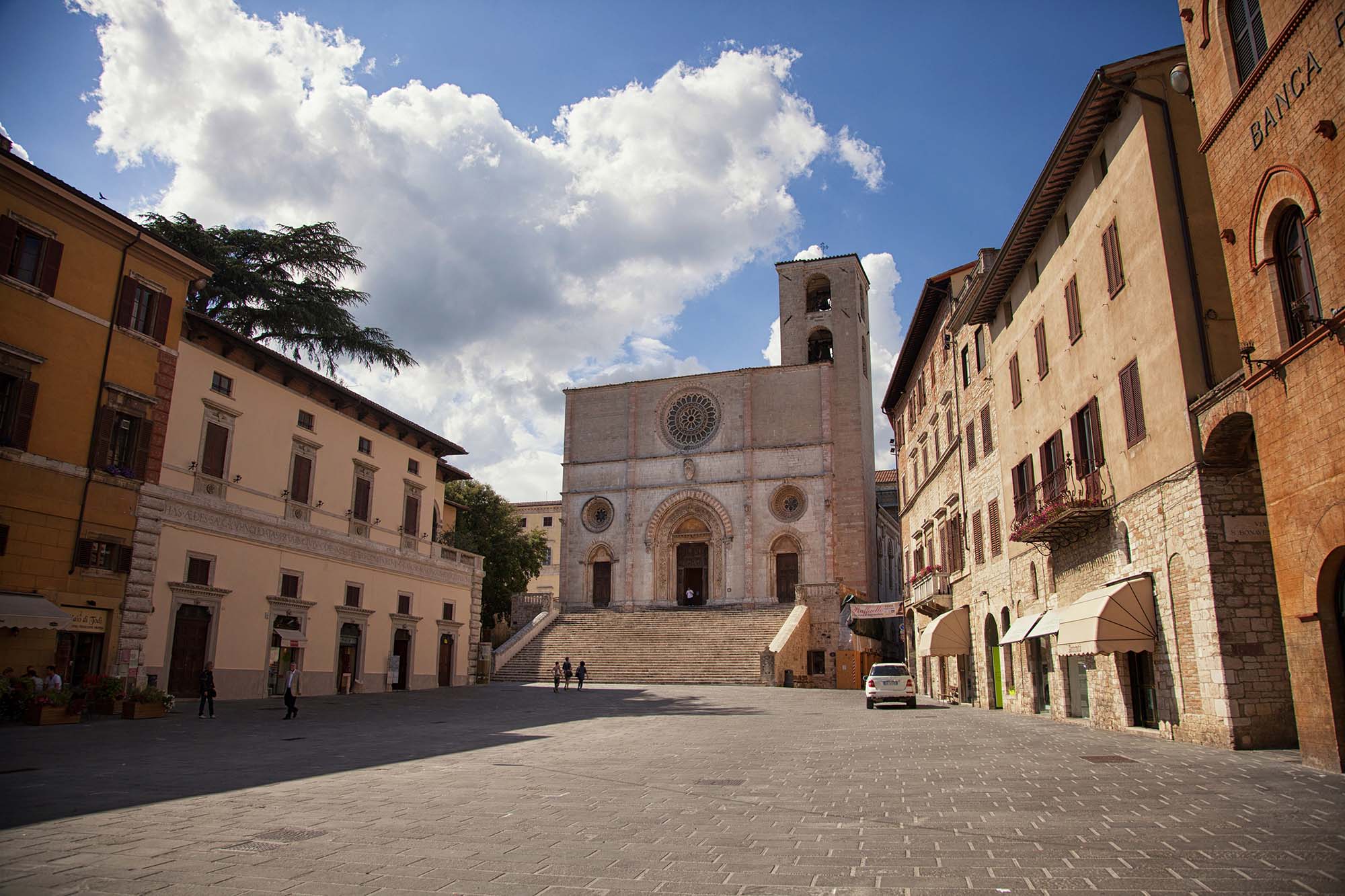 Piazza del Popolo in Todi with the Romanesque Cathedral, the staircase, and the bell tower, surrounded by historic buildings.