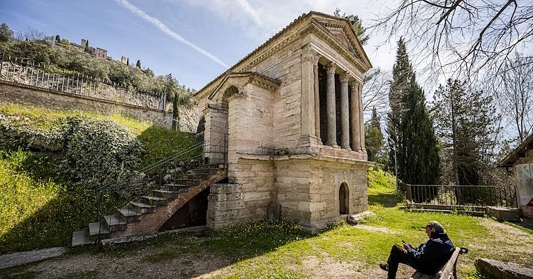 Vista della scalinata laterale e della fronte con colonne del Tempietto sul Clitunno immerso nel verde