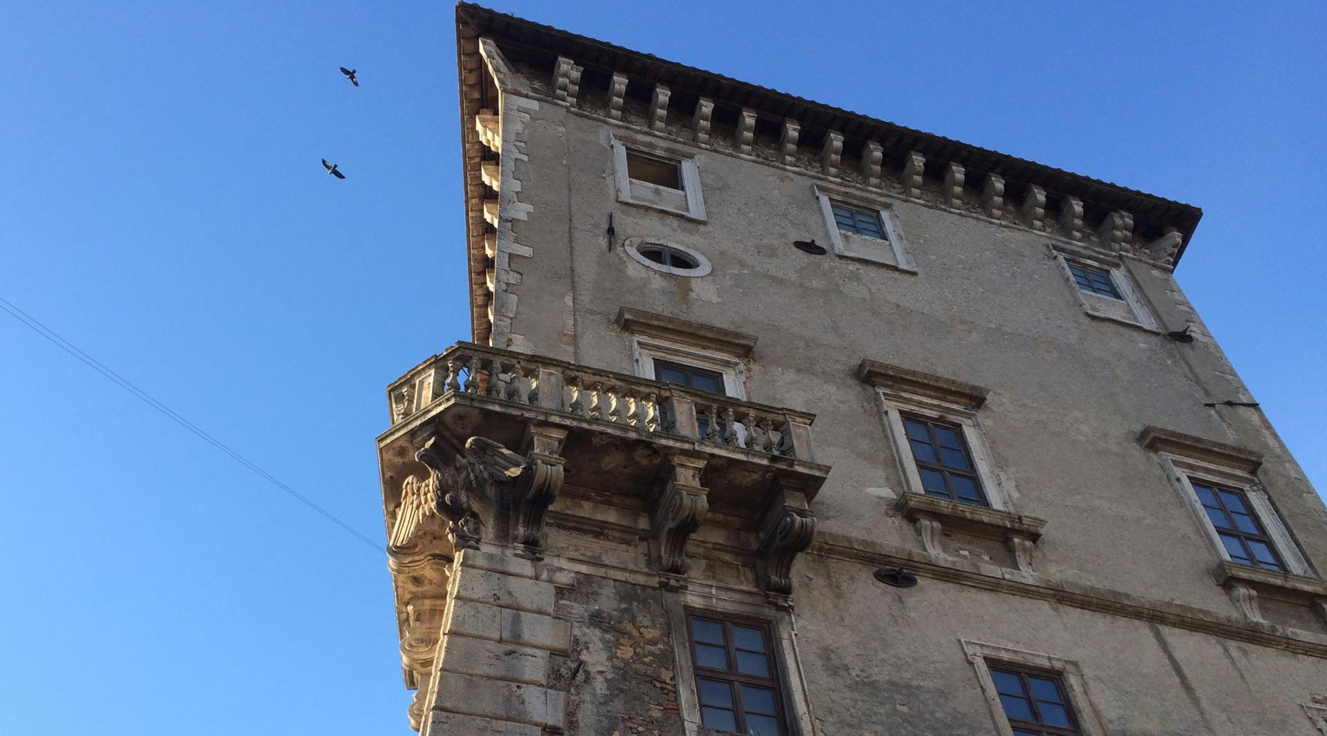 Schloss Giove von unten gesehen, mit steinernem Balkon und historischen Fenstern unter blauem Himmel.