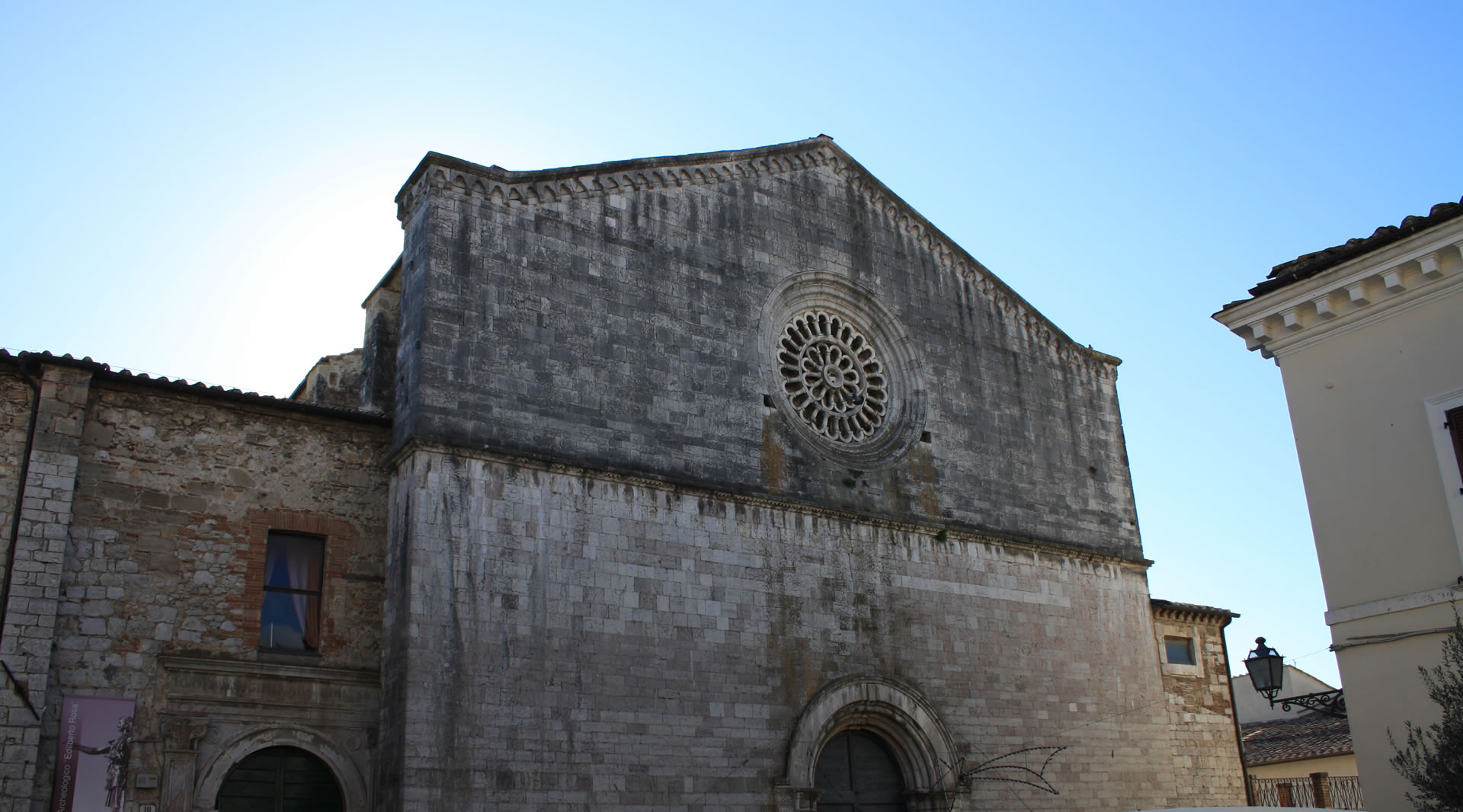 Facade of the Church of Saint Francis in Amelia with a central rose window and stone portal under a clear sky