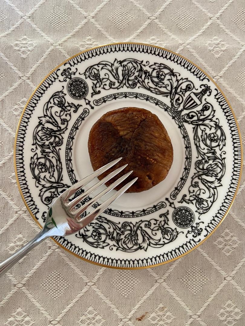 A stuffed dried fig on a black-and-white decorated porcelain plate, with a fork beside it.