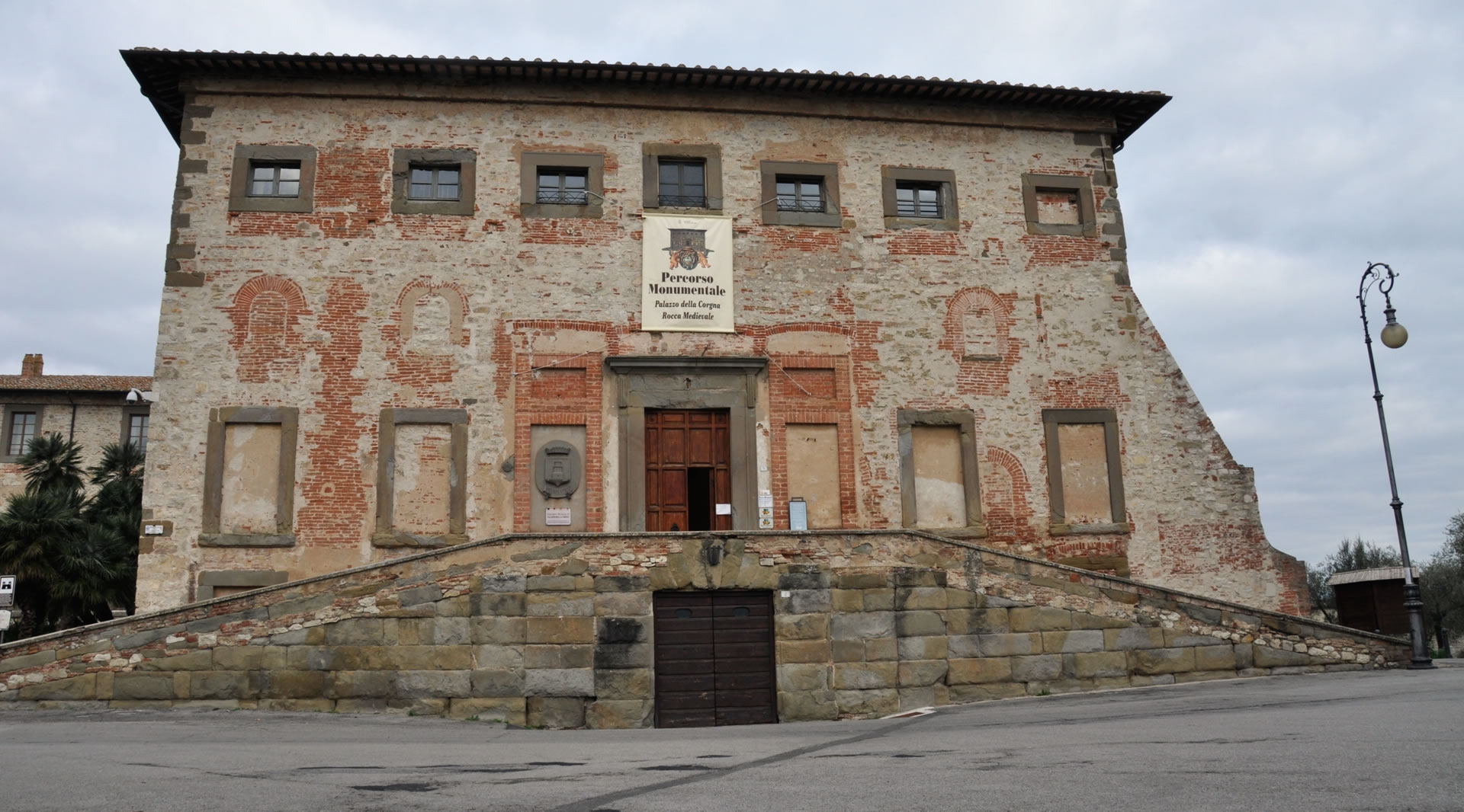 Main façade of the Palazzo della Corgna in Castiglione del Lago, characterised by exposed brickwork and an entrance staircase.