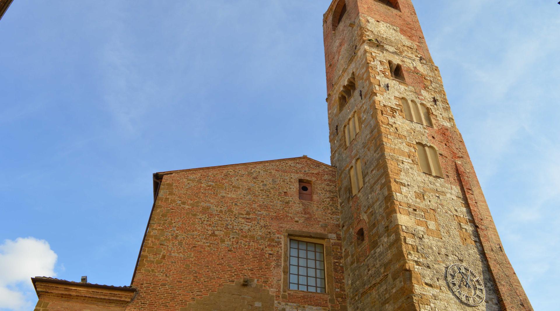 Front perspective of the church of santi Gervasio e Protasio, with its imposing facade and the bell tower towering over it.