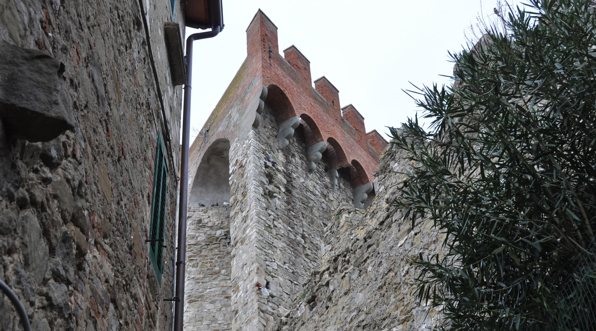 Detail of the Tower of the Rocca di Passignano, highlighting its distinctive triangular shape in masonry that stands out in the landscape.