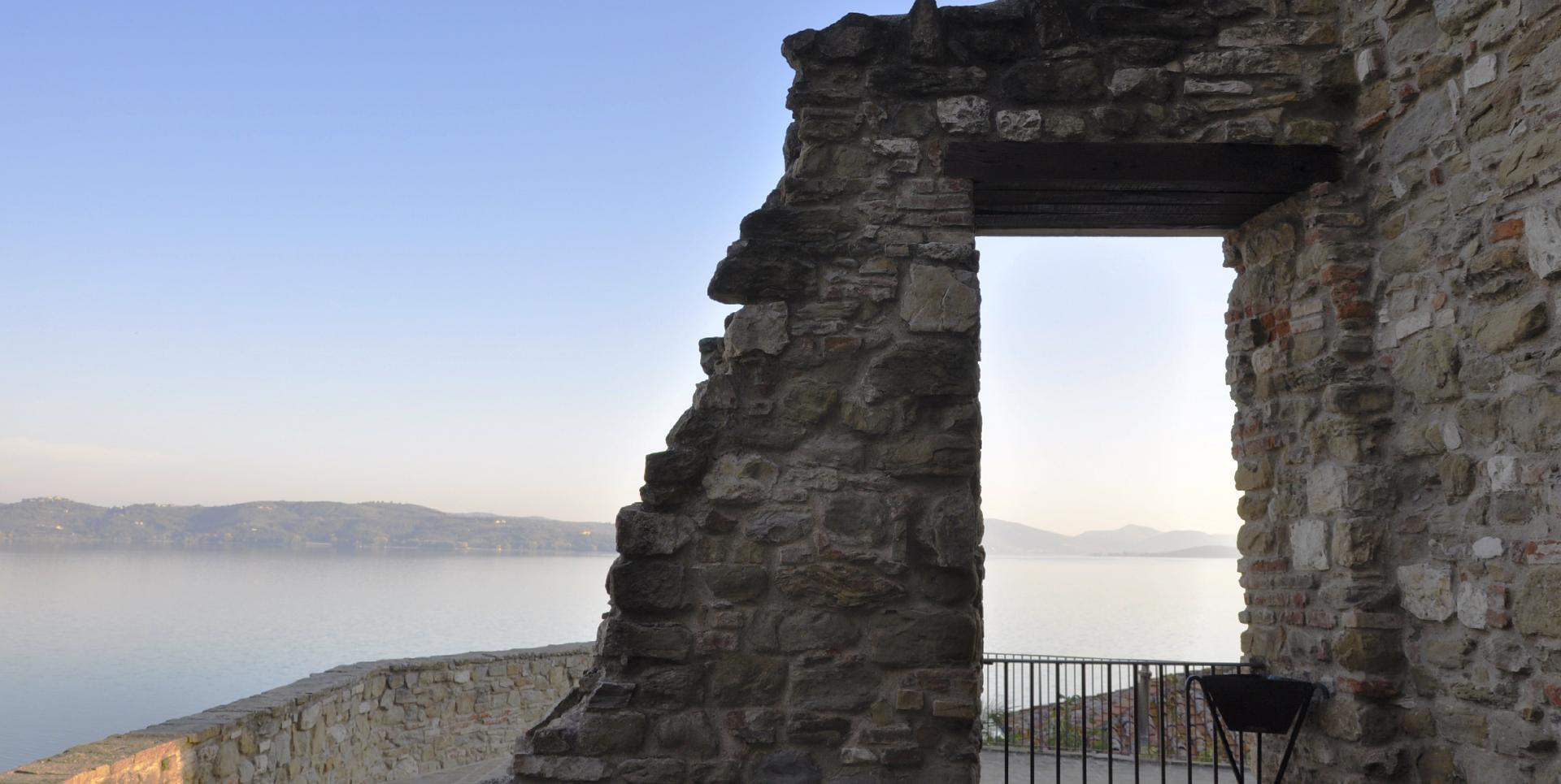 View from the top of the Rocca, where an arrow slit opens up to offer a stunning view of Lake Trasimeno in the background, framed by the ancient walls.