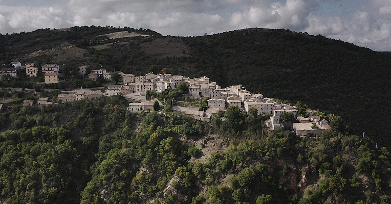 The layout of the medieval castle of Poggiodomo perched on a rocky spur amidst unspoilt nature and green woods