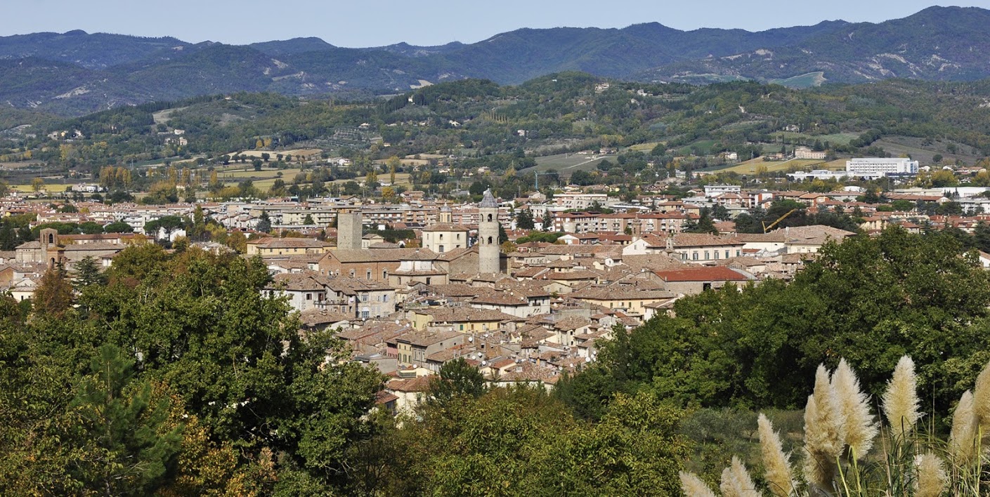 Panoramic view of Città di Castello, with its historic rooftops, towers, and bell towers, surrounded by the green Umbrian hills.