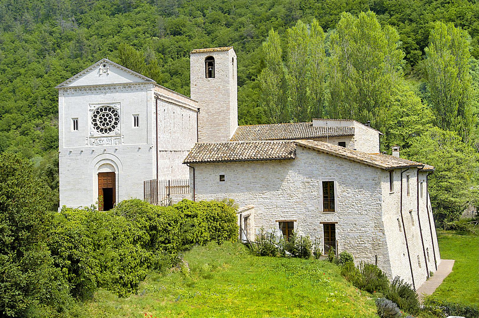 Abbey of Saints Felice and Mauro surrounded by nature in springtime with the church on the left of the picture, the bell tower in the centre and the structures of the ancient abbey on the right, now used as accommodation