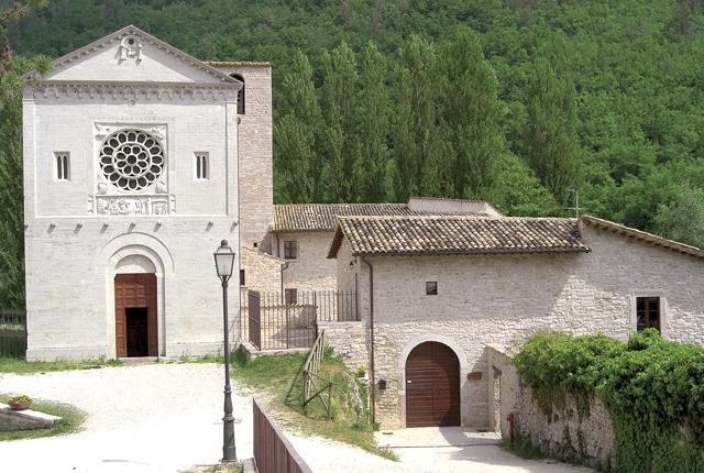 Entrance to the church and structure of the abbey of Saints Felice and Mauro. The entrance to the church features a Romanesque-style doorway with a central rose window.