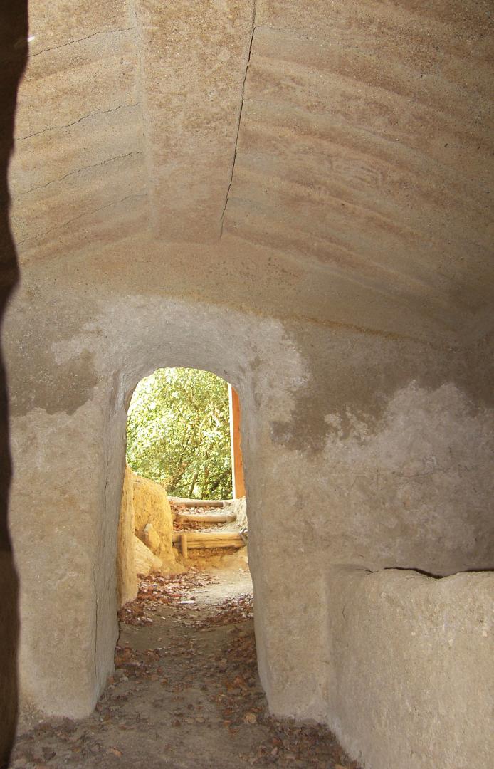 Rock-carved inner corridor with an arched ceiling, leading outward into the surrounding natural landscape.