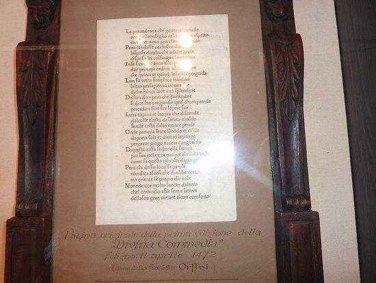 Page from the first edition of the Divine Comedy displayed in a case, with an explanatory caption and an intricately carved wooden frame.