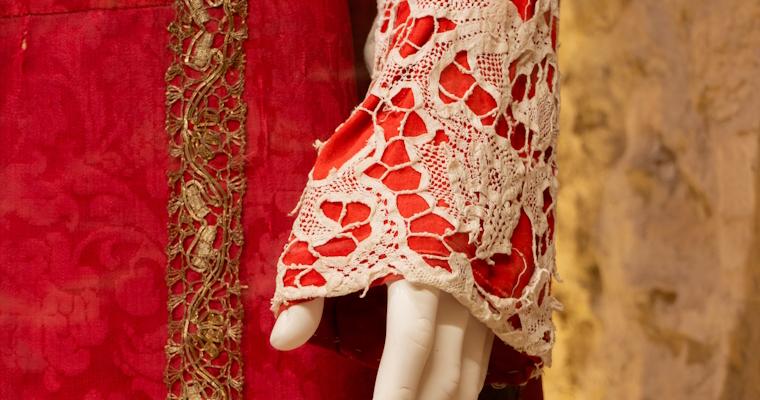 Close-up of a red fabric gown on the statue of the Madonna, worn for a specific liturgical period of the year.