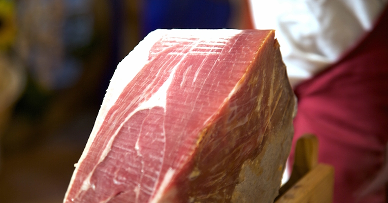 Hand-sliced Prosciutto di Norcia PGI, showcasing the distinctive red colour of the meat and white fat marbling