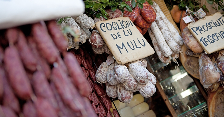 A display of norcineria products, with a sign reading “coglioni de lu mulu”, suggesting the name of the sausage on display