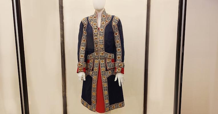 Elegant blue and red livery with gold decorations, displayed in a case in the costume room