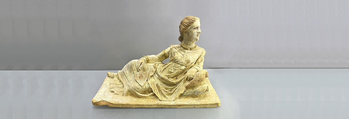 Lid of Etruscan urn with a richly dressed and coiffed female figure, with traces of colour visible on her hair
