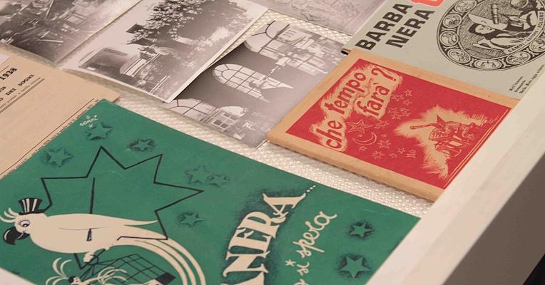 Some coloured booklet almanacs and some photos kept inside a display case.