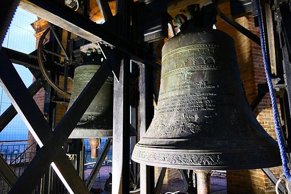 Decorated bronze bells mounted in a wooden structure inside a bell tower