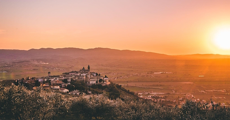 Panorama of Trevi with the setting sun illuminating the valley and surrounding olive groves.