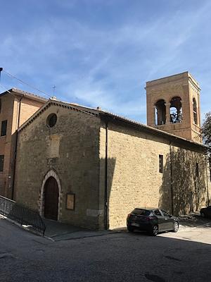 Vista della chiesa di Sant’Agostino a Gualdo Cattaneo, con facciata in pietra e il campanile che si staglia contro il cielo.