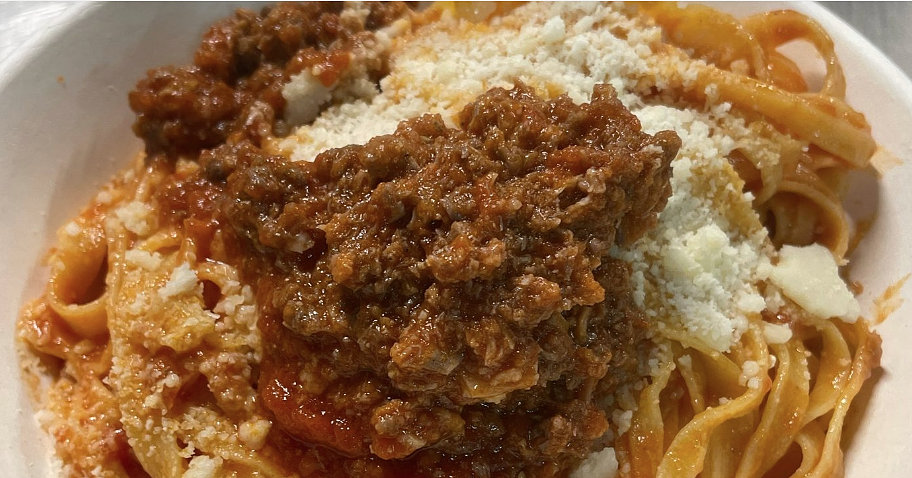 Plate of fresh tagliatelle served with goose ragu and a sprinkling of grated cheese.