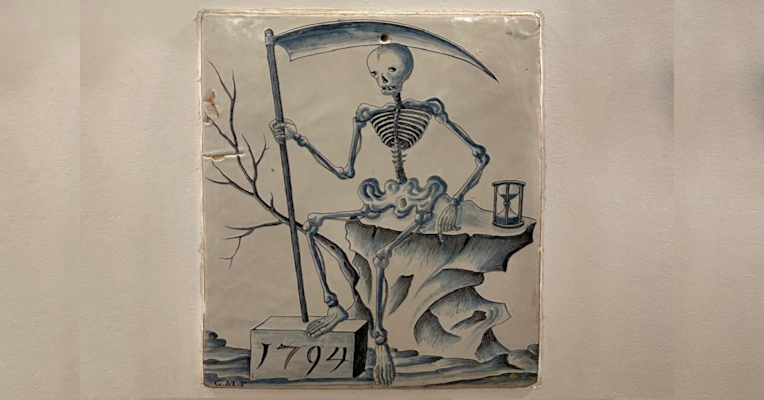 Keramikillustration von 1794 mit einem Skelett mit Sense, das neben einer Sanduhr auf einem Felsen sitzt.