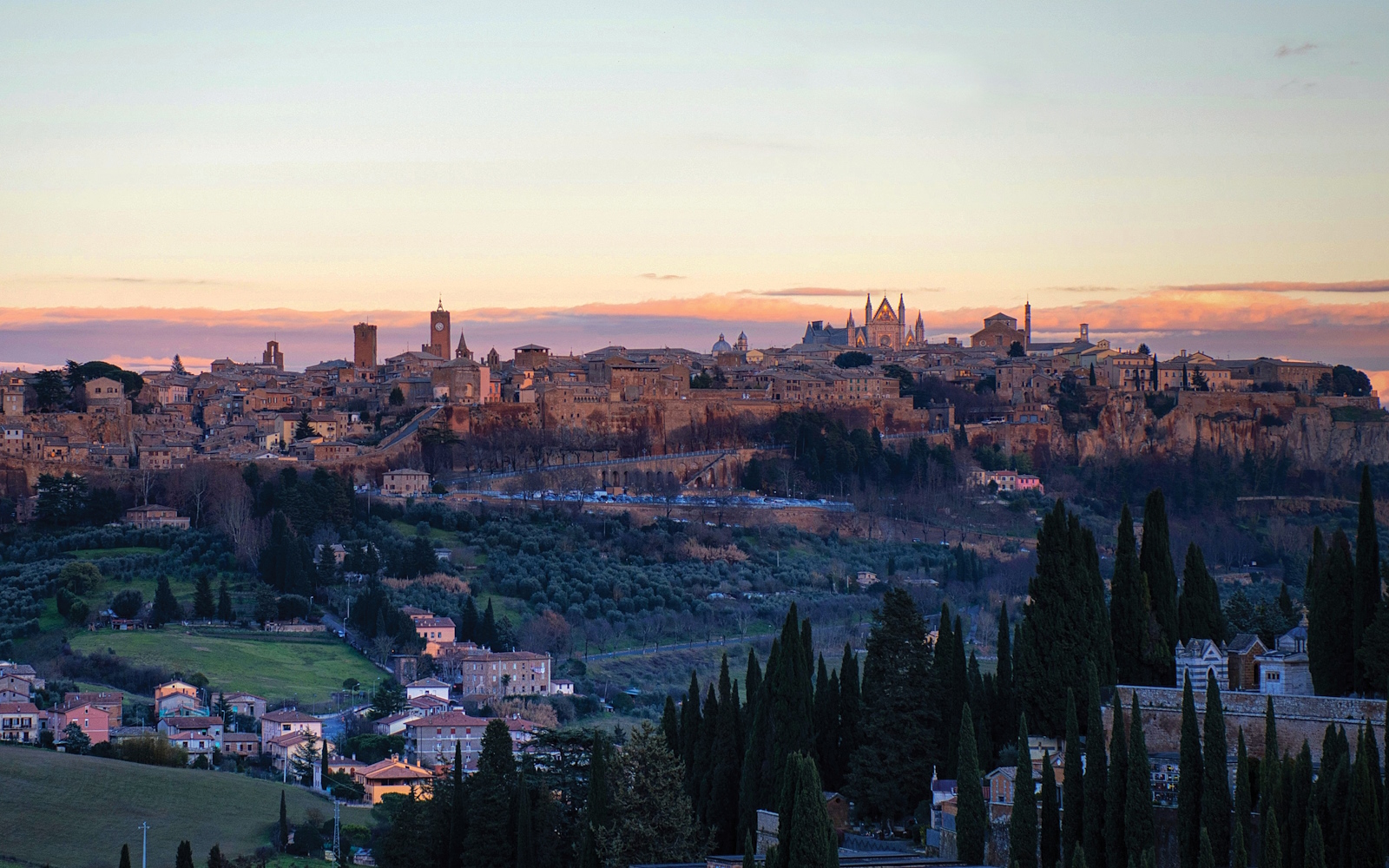 Vista panoramica della città di Orvieto illuminata dalla luce del tramonto, adagiata sulla sua rupe tufacea.