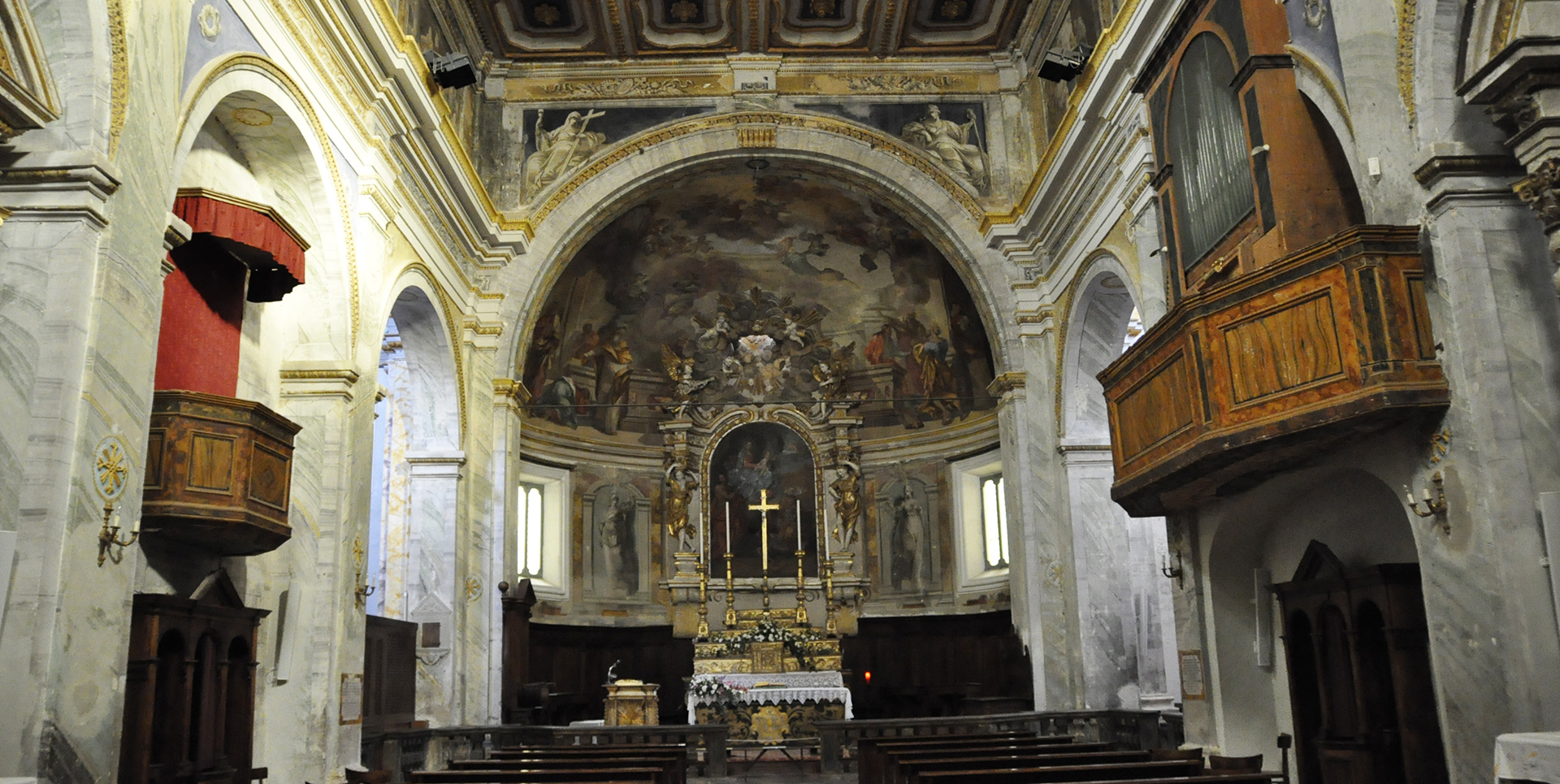 Interior of the Collegiate Church of Santa Maria Assunta and San Gregorio in Montone, with Baroque altar and frescoes.