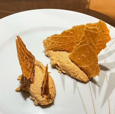 Eis auf einem weißen Teller mit gebrochenen, knusprigen Waffeln darauf.
