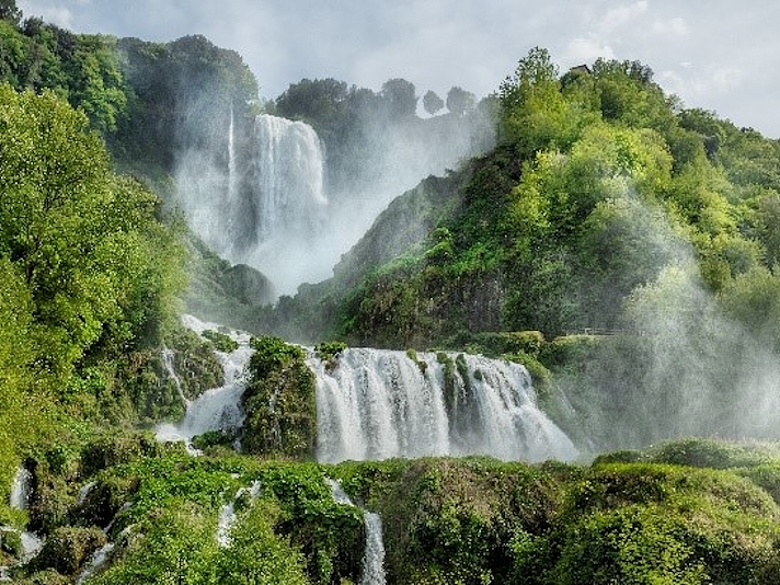 Blick auf die Marmore-Wasserfälle mit mehreren Wasserfällen zwischen Vegetation und Felsen.