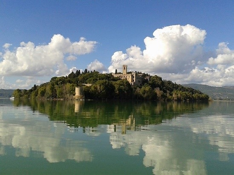 Blick auf die Isola Maggiore am Trasimenischen See unter einem bewölkten Himmel.