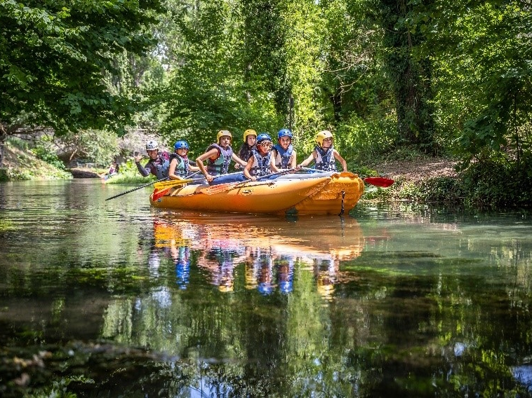 Gruppe von Personen in einem Schlauchboot während einer Rafting-Tour auf dem Fluss Nera, umgeben von Vegetation.