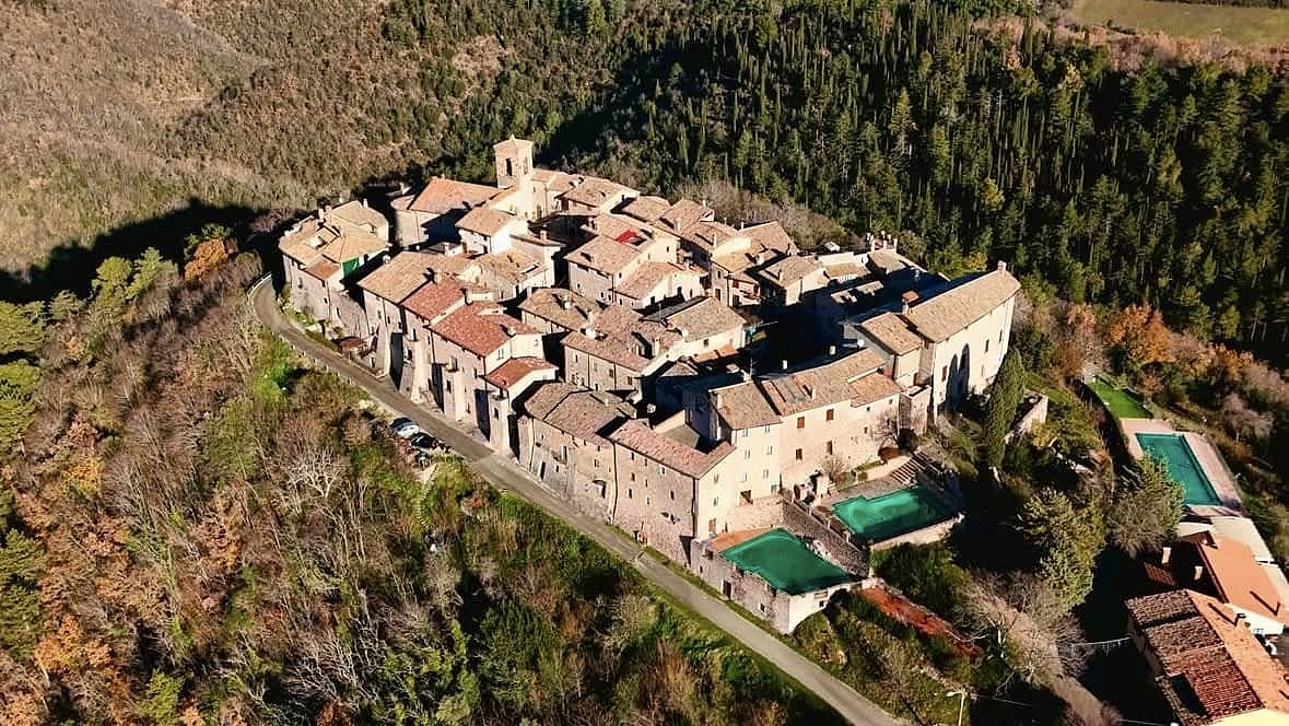 Luftaufnahme der mittelalterlichen Burg Macerino in den Monti Martani, umgeben von umbrischen Wäldern
