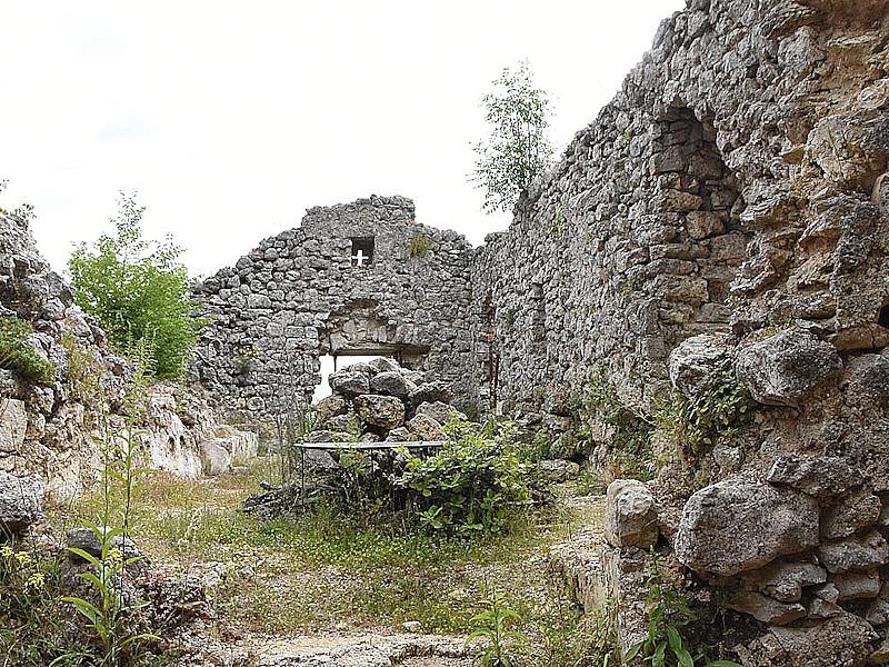 Ruinen der Kirche Santa Maria Maddalena neben dem franziskanischen Kloster von Collicello mit teilweise eingestürzten Mauern und wilder Vegetation.