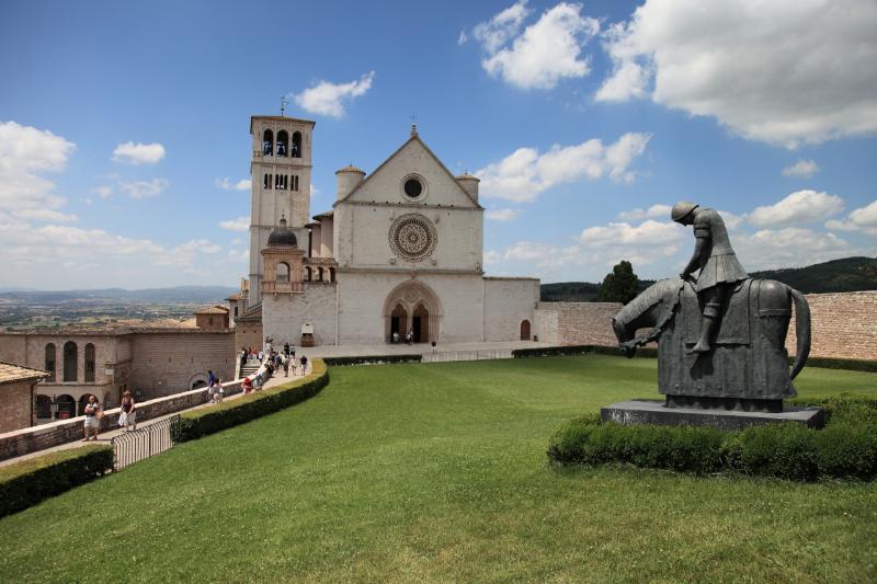 Fachada da Basílica de Santa Maria dos Anjos em Assis com a praça em frente e céu nublado