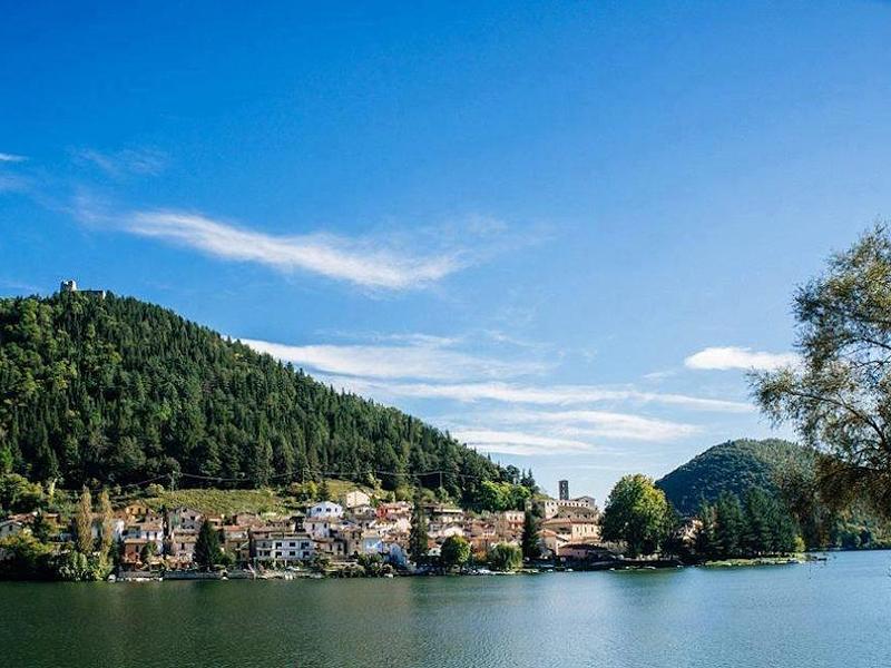 The village of Piediluco, at the foot of the mountain with the remains of the fortress, overlooking the lake on a sunny day.